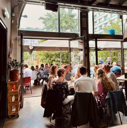 Gasten aan tafel bij de geopende pui met het terras erachter