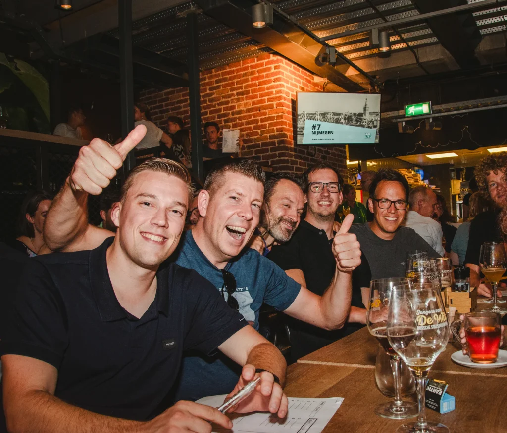 Groep collega's aan de lange tafel tijdens de pubquiz in het café