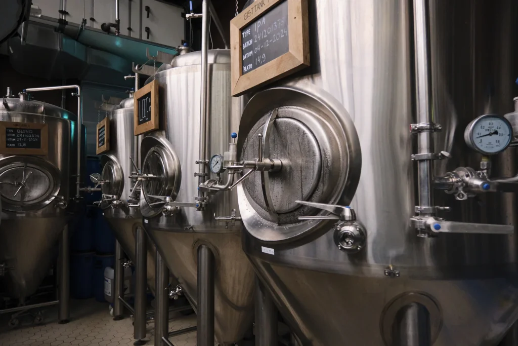 Rij roestvrijstalen gistvaten met krijtbordjes in de brouwerij