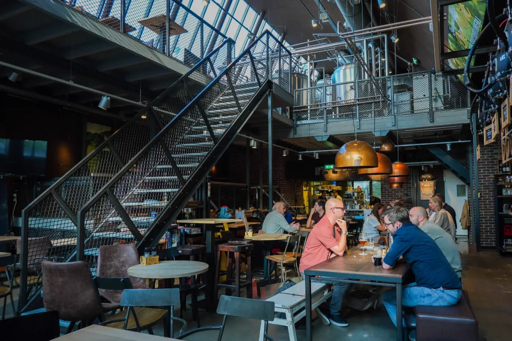 Gasten aan tafel in het restaurant, met de brouwketels op de verdieping