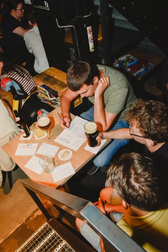 Van bovenaf: quizteam vult het antwoordformulier in aan een cafétafel